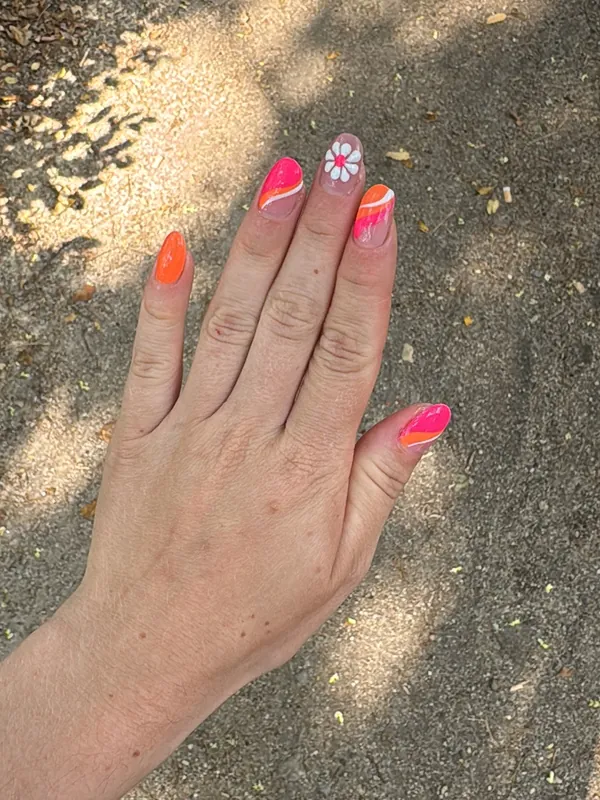 Ongles fluo orange et rose, une fleur sur l'annulaire