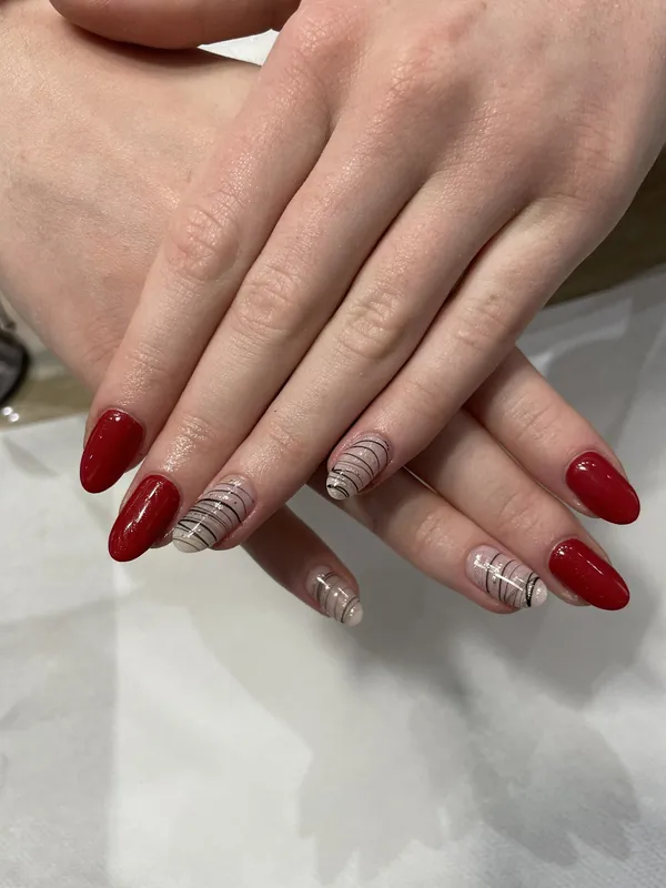 Ongles amande rouge laqué, deux ongles nude à rayures fines